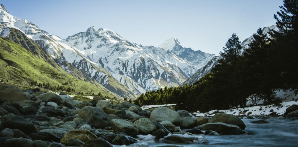 rocky river with snow covered mountains in the distance