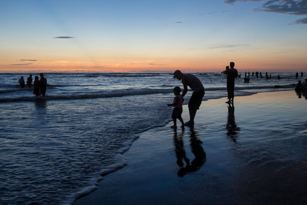A group of people standing on top of a beach next to the ocean
